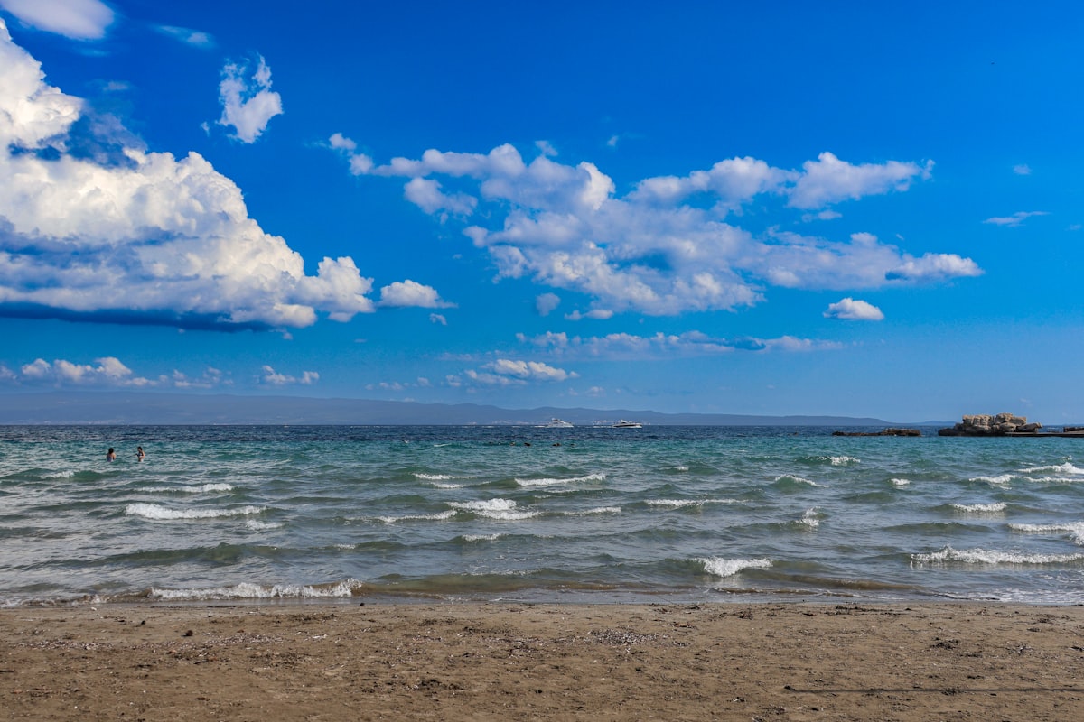 A pebble beach on the Split coast with clear Adriatic water and swimmers, Croatia